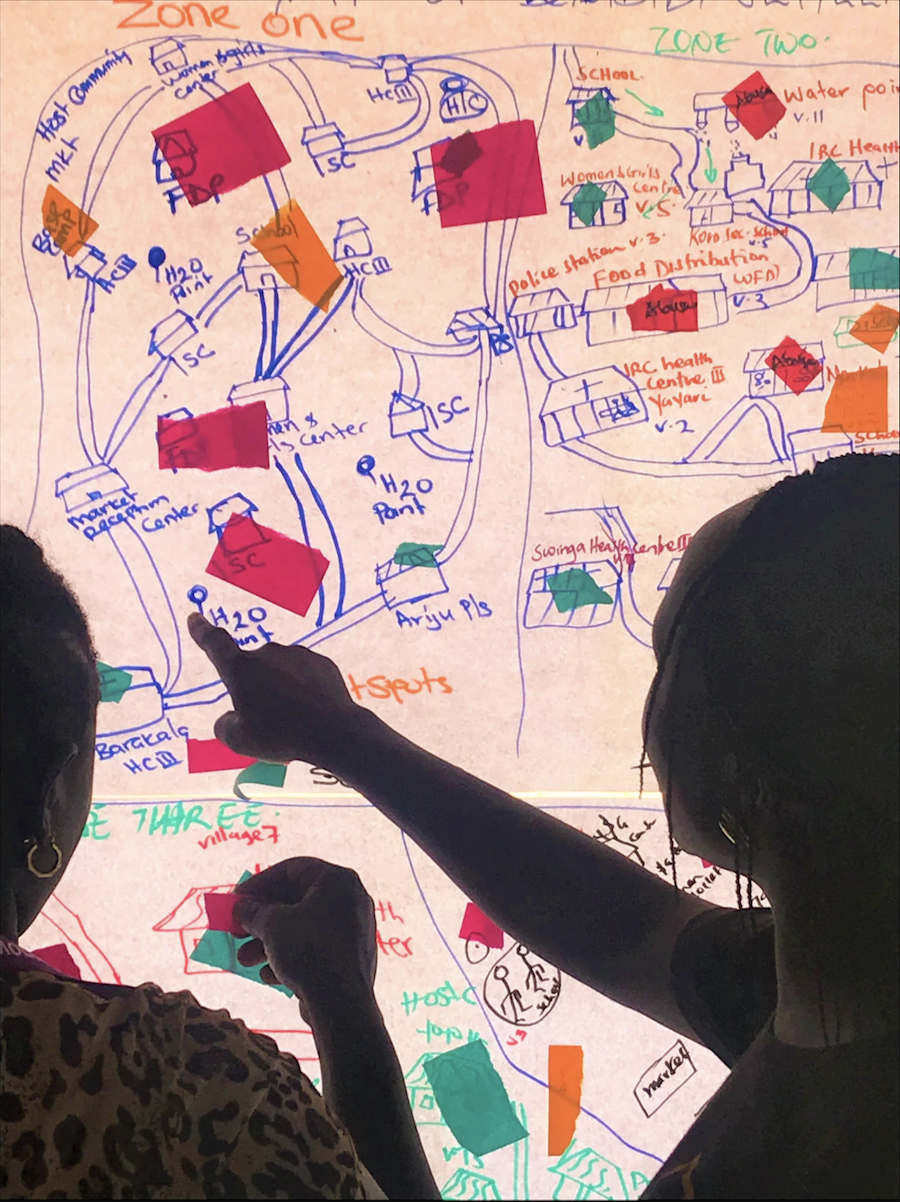 two women review sticky notes and map on white board