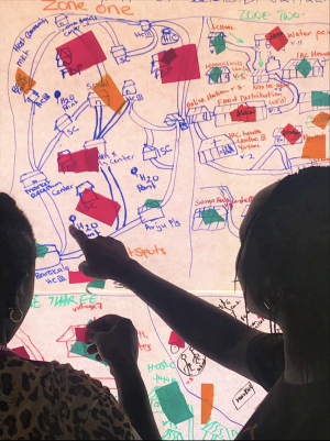two women review sticky notes and map on white board